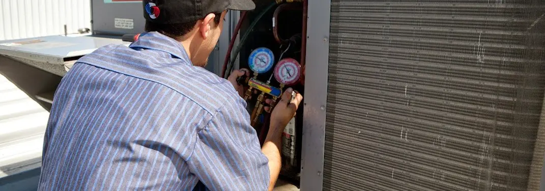 HVAC technician servicing a condenser unit in West Haverstraw